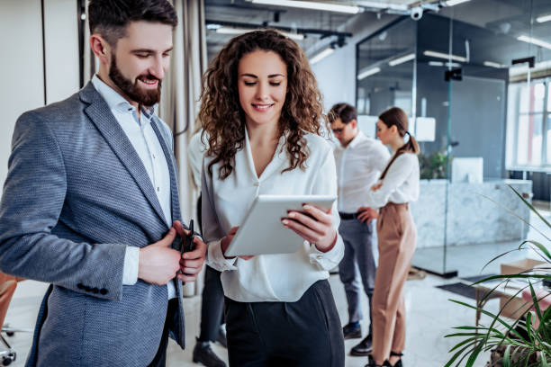 Business professionals discussing a project on a tablet in a modern office, highlighting joint ventures in Dubai.