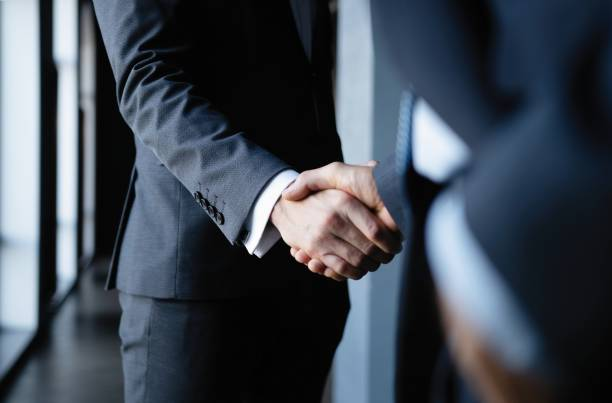 Two business professionals in suits shaking hands, symbolizing a joint venture partnership in Dubai.