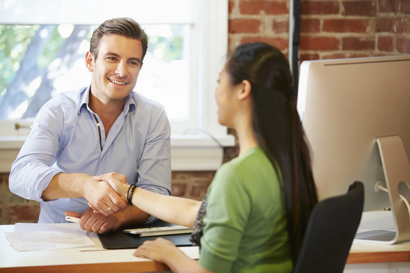 Two people shaking hands in an office setting.